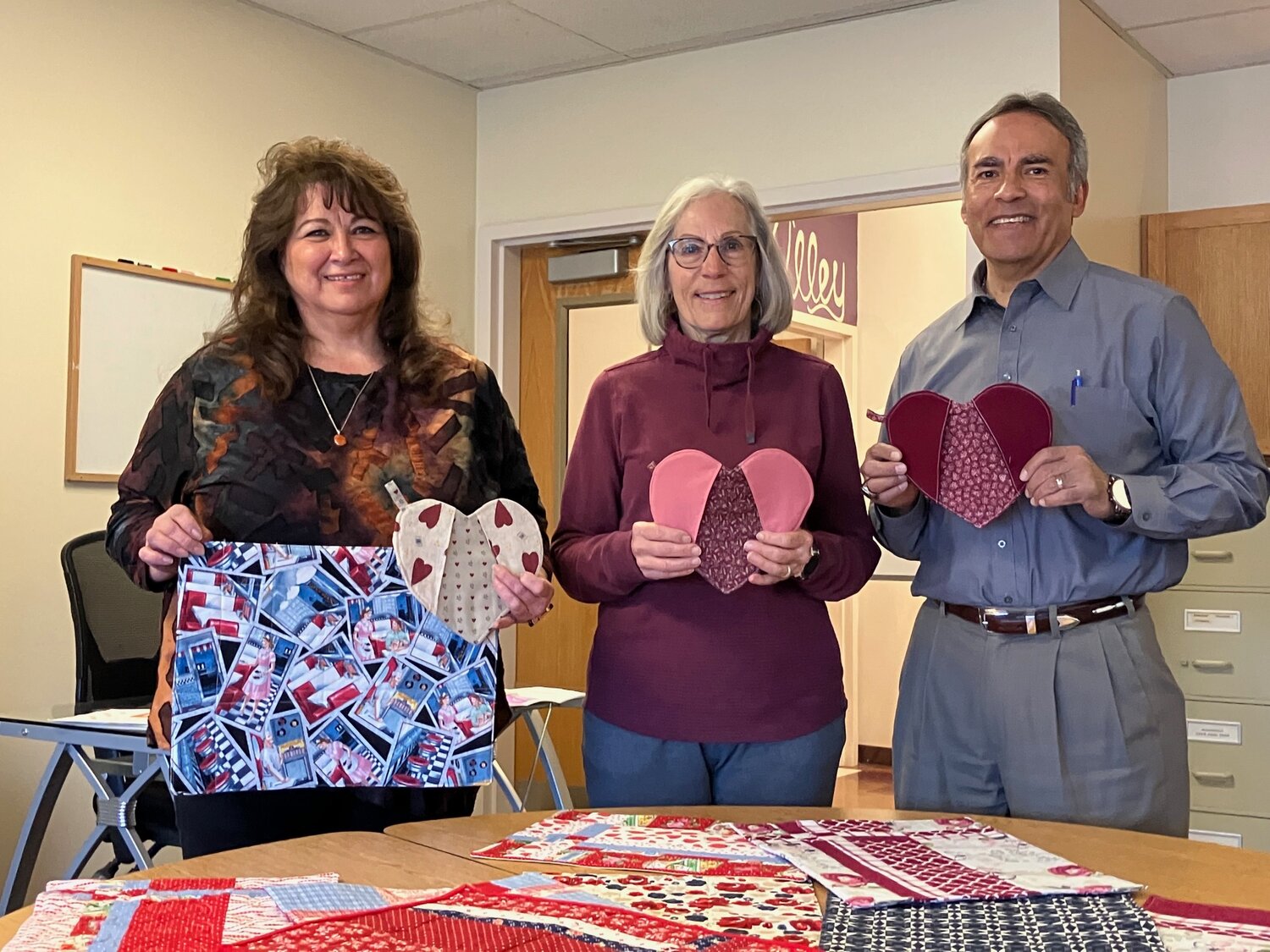 The Pagosa Piecemakers Quilt Guild teams up with Archuleta Seniors Inc. (ASI) for a special Valentine&rsquo;s Day surprise. The ladies of the guild have been busy making placemats which have a Valentine&rsquo;s theme on one side, and another fabric or theme on the reverse side, allowing them to be used after Valentine&rsquo;s Day. In addition to the placemats, one of the members made heart-shaped potholders for each family. Pictured is guild member Lorraine Hesselbach delivering the placemats to ASI staff Barbara Norega and Ricardo Martinez.