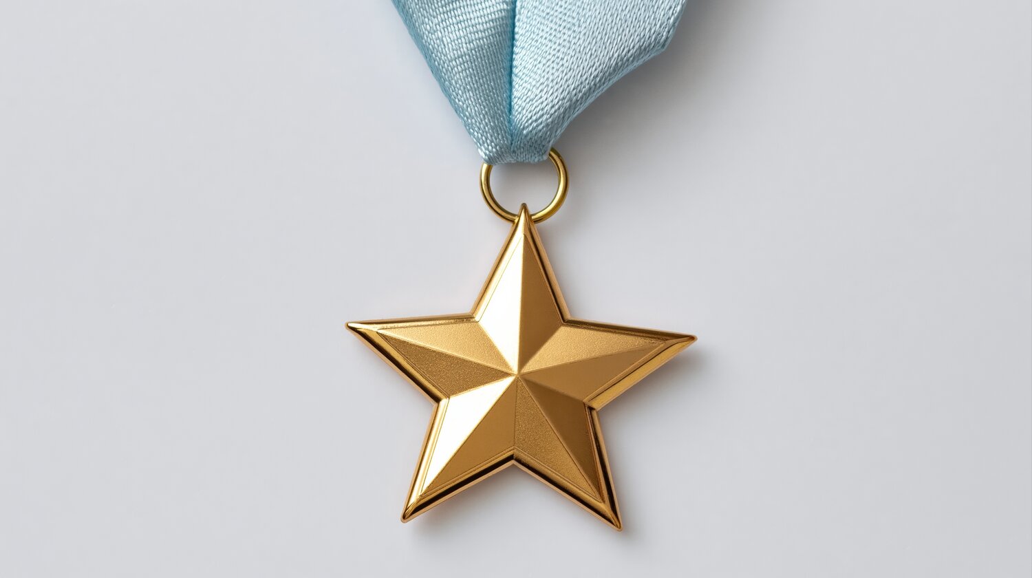 A close up view of a golden five pointed star shaped military style medal attached to a light blue silk ribbon against a plain white background