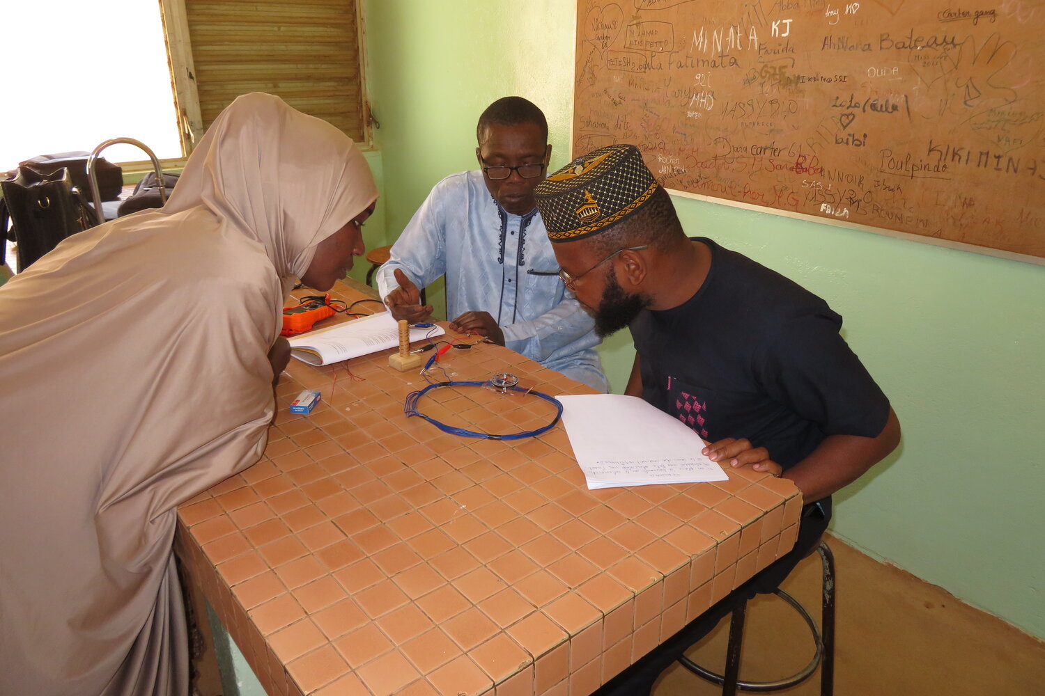Teachers are the direction of the magnetic field generated by a current in a wire. The lead teacher is demonstrating the right-hand rule. Understanding basic principles of electromagnetism is essential for building and repairing electric motors. Photo from 2023 workshops in Niger.