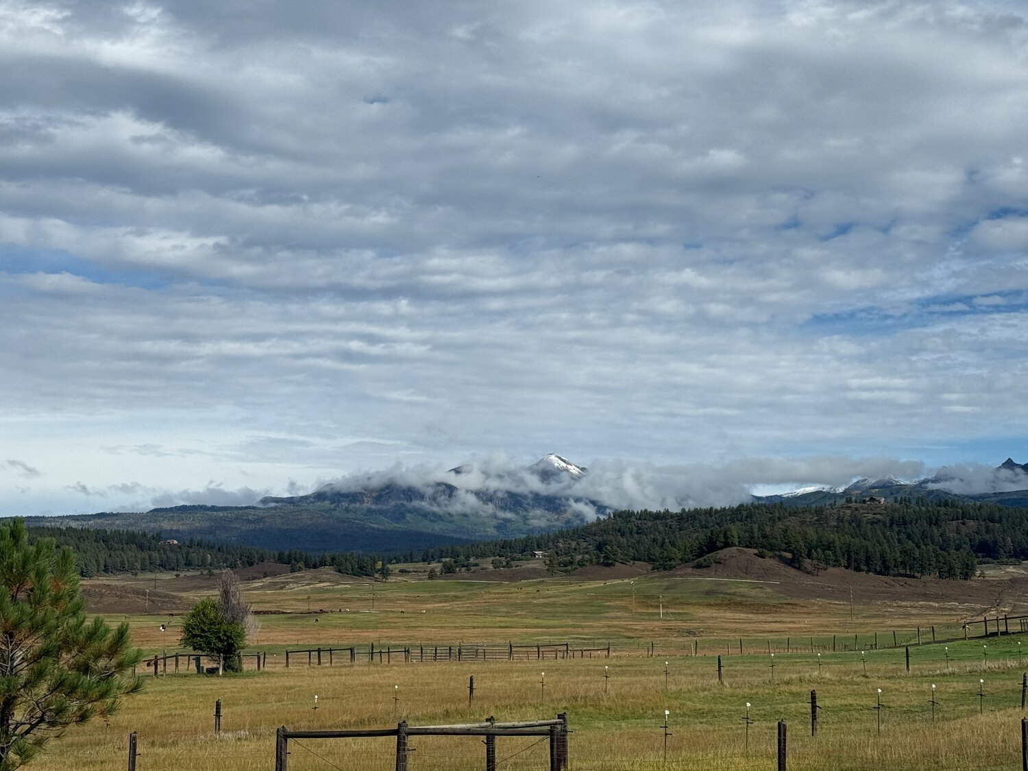 Snow-dusted mountains peek through the clouds after the areas mountains received their first snowfall of the season on Tuesday, Sept. 29.