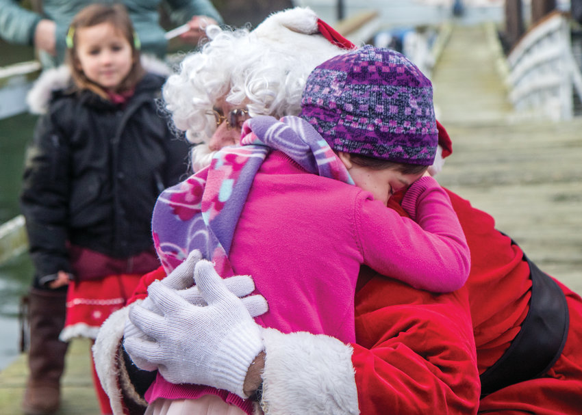 Four-year-old Juneau McKinnon gives Santa Claus a big hug as he steps off the boat and heads up the dock to the Nordland General Store on Marrowstone Island.