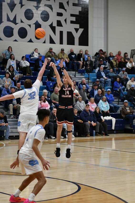 Cooper McElroy (14) fires from downtown. McElroy finished with 17 points and four rebounds in the win at Moore County.