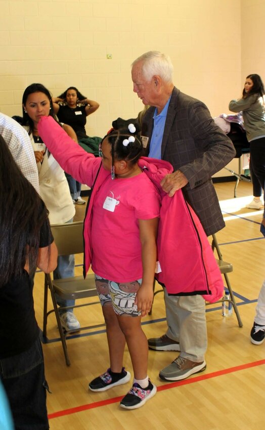 Every child received a warm coat at East Side. State Rep. Pat Marsh helps out with trying on a new coat.