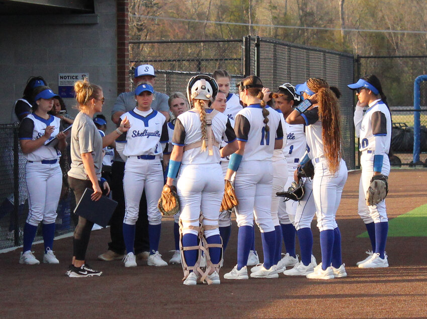 Shelbyville Central HC Kailey Snell (left, grey) talks to her team between innings in the district opener against Cookeville. Snell picked up her first career win as head coach on Wednesday at Murfreesboro Central Magnet.