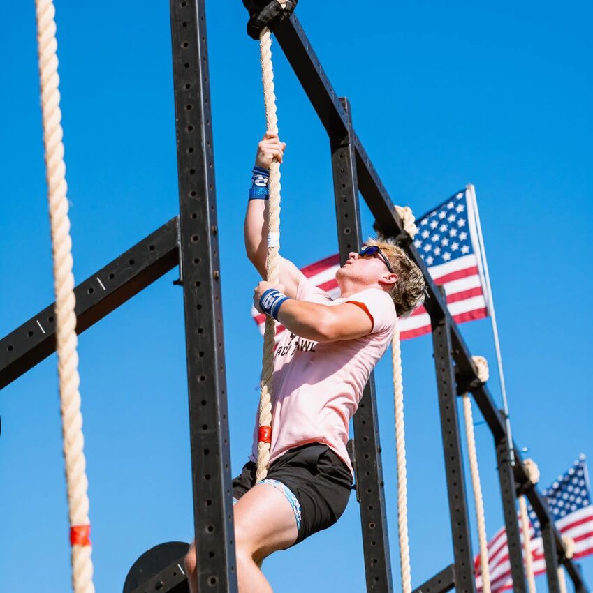 Corbin Riley (pictured) completes one rep on the 15-foot rope climb during competition.