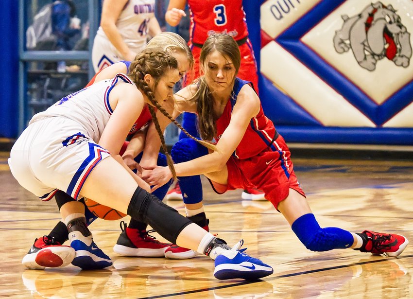 Lindsey Hornaday, left, battles Crimson Bryant and Bella Crawford for a loose ball, resulting in one of dozens of jump ball calls during the Wood County square-off last Tuesday in Quitman’s Ballard Gym.