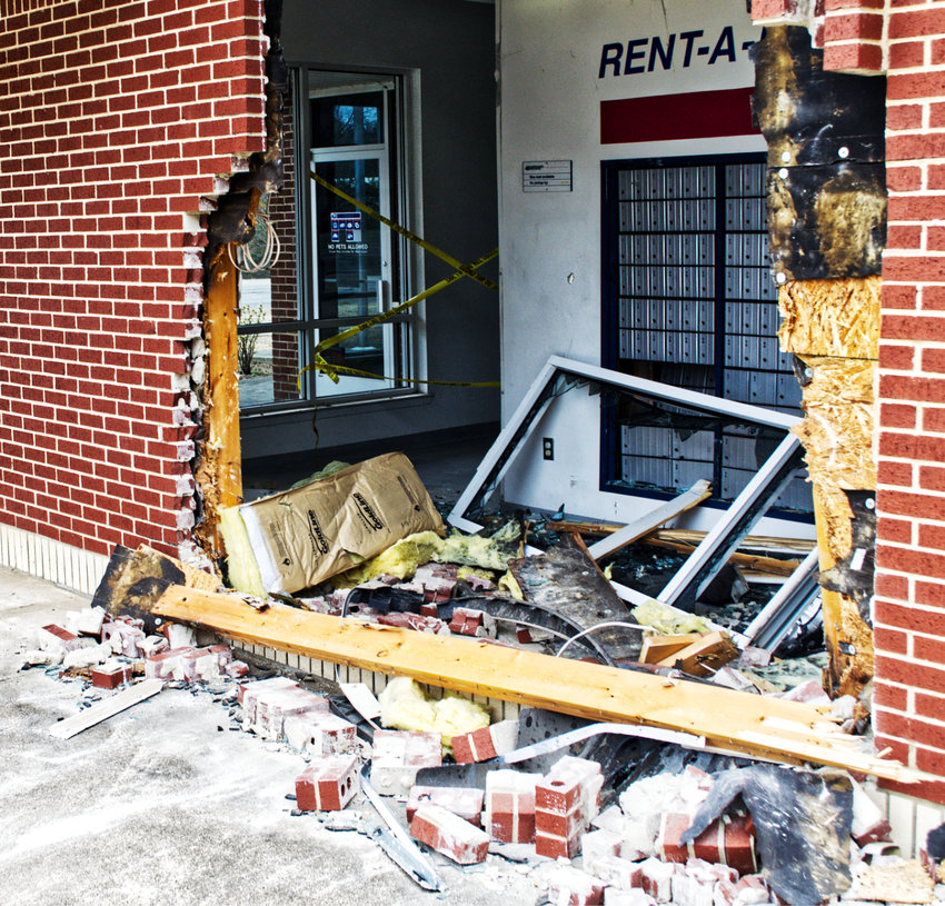 The exterior of the east side of the Post Office building in Mineola, with a hole just wider than the vehicle that smashed through the brick wall.