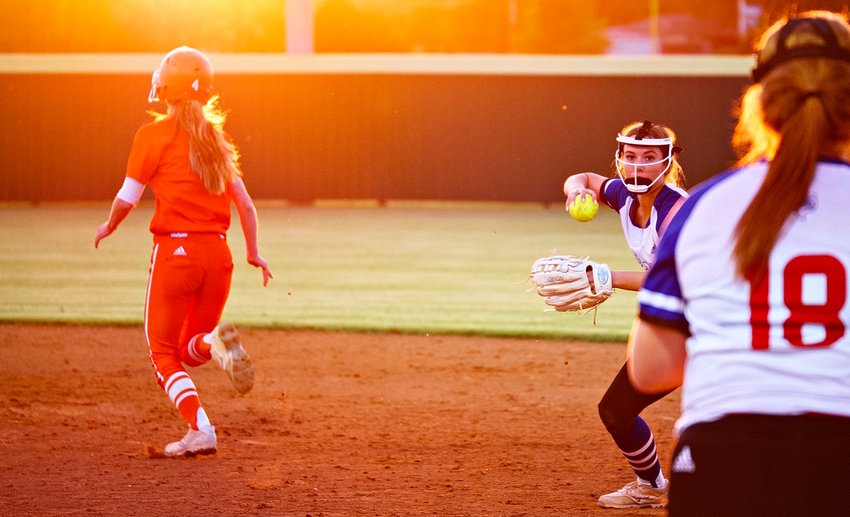 Lindsey Hornaday makes a play to Reiny Luman at first base as Emily Wiley makes her way to second, into the setting sun.
